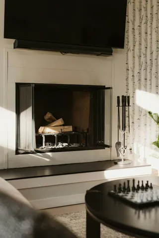 Serviteur de cheminée en fer forgé noir, posé près d'un foyer dans un salon moderne